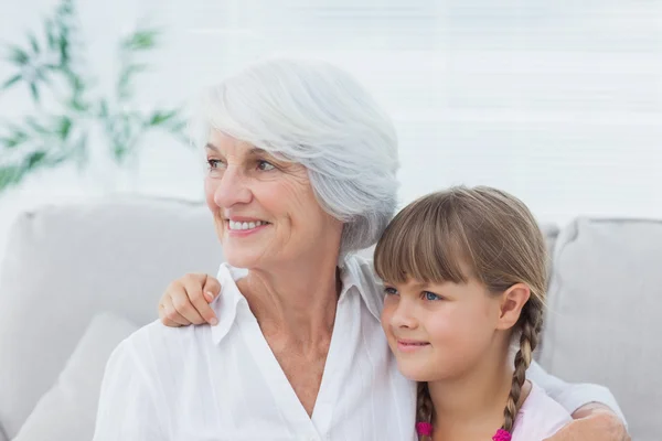 Nettes Mädchen und Großmutter sitzen auf der Couch — Stockfoto