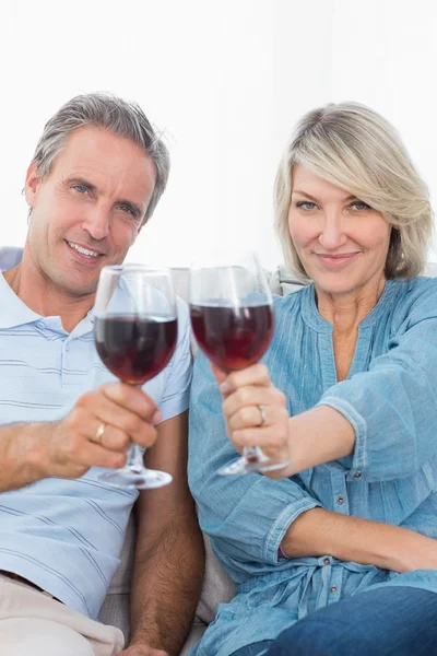 Пара тостов за камеру с красным вином на диване — стоковое фото