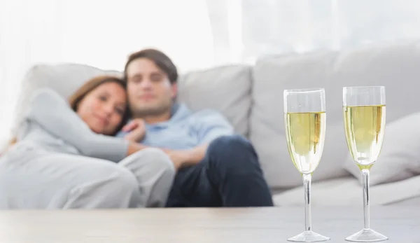 Iki şampanya flüt ile bir kanepede rahatlatıcı — Stok fotoğraf