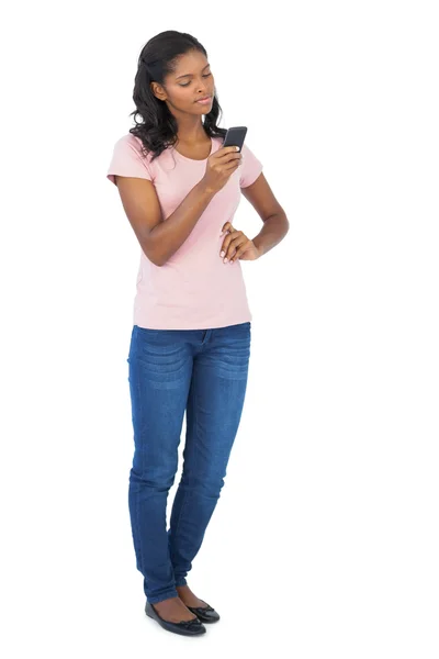 Mujer joven mirando su teléfono móvil con la mano en la cadera — Foto de Stock