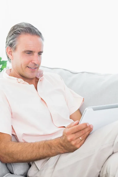 Gelukkig man ontspannen op zijn bank gebruiken, tablet pc — Stockfoto