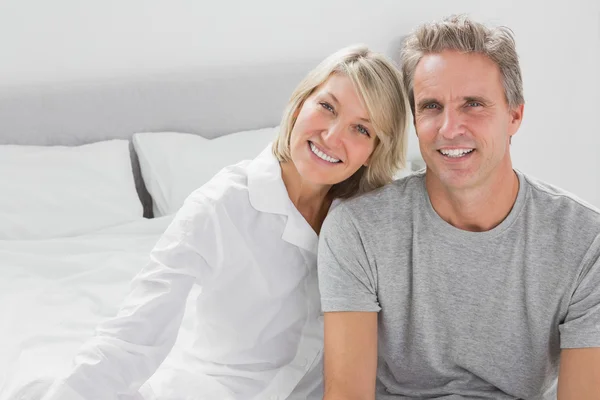 Cheerful couple sitting on bed — Stock Photo, Image