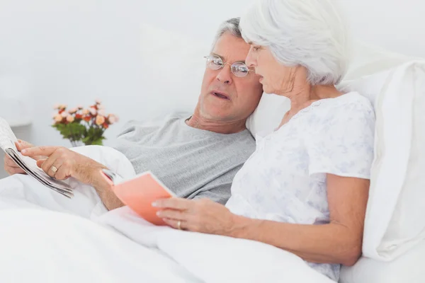 Pareja madura mirando un periódico — Foto de Stock