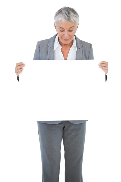 Donna d'affari in possesso e guardando segno bianco su sfondo bianco — Foto Stock