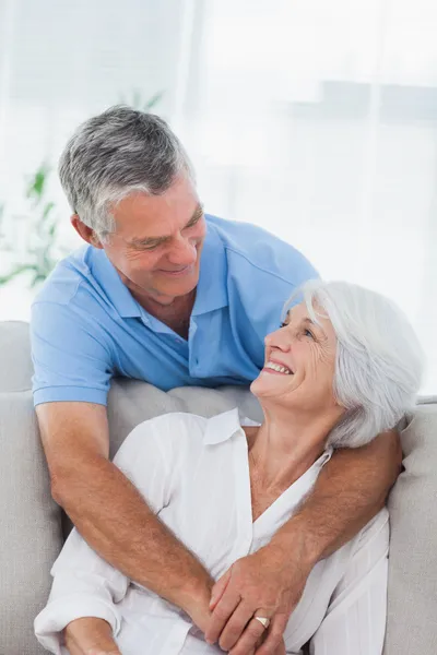Man hugging wife who is sitting on the couch — Stock Photo, Image