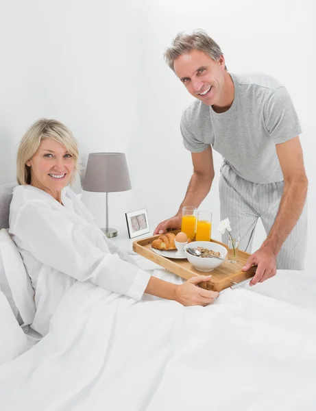 Glücklicher Mann, der seiner Partnerin im Bett frühstückt — Stockfoto