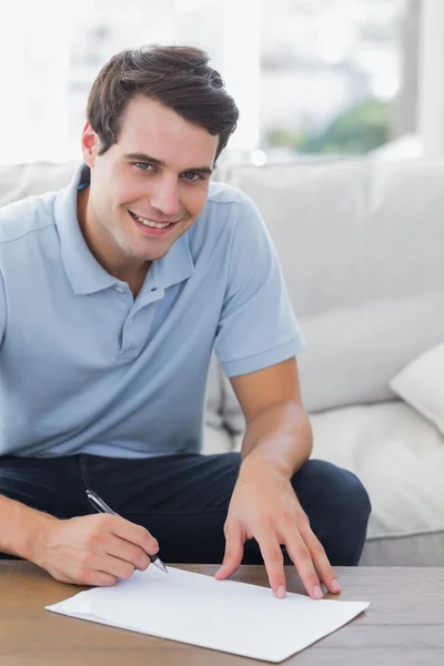 Portret van een man op een papier schrijft terwijl hij is zat op een bank — Stockfoto