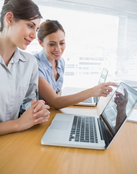 Businesswoman pointing to something on laptop for colleague — Stock Photo, Image