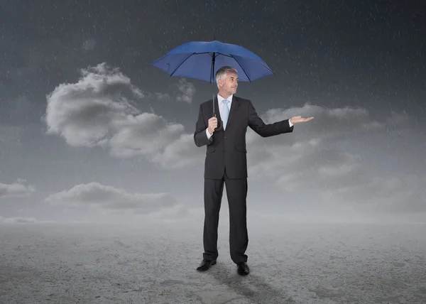Businessman holding a blue umbrella — Stock Photo, Image