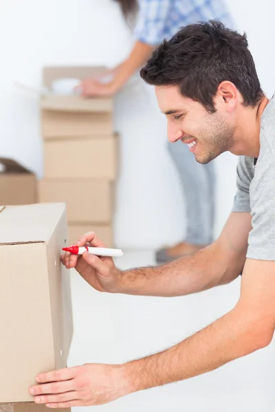 Man writing with a marker on a moving box — Stock Photo, Image