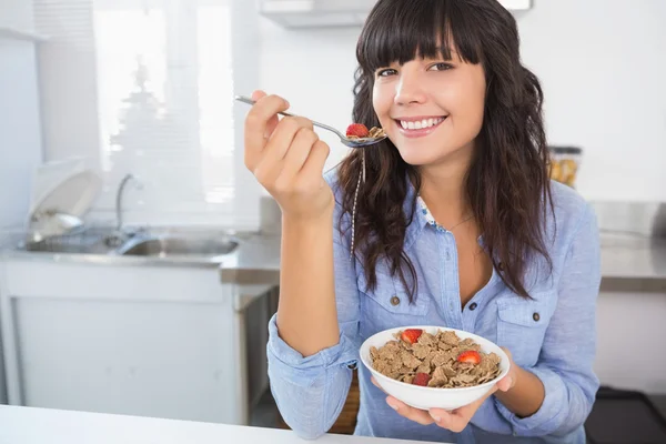 Morena atraente comendo tigela de cereais e frutas — Fotografia de Stock