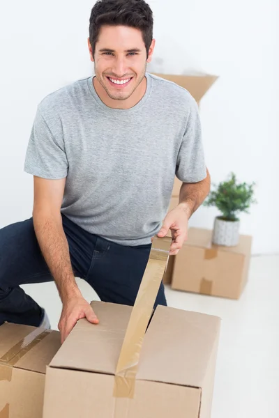 Homem alegre embrulhando uma caixa — Fotografia de Stock