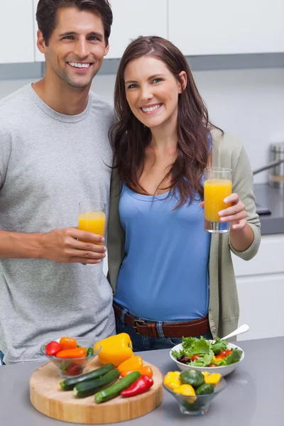 Encantada pareja sosteniendo un vaso de jugo de naranja — Foto de Stock