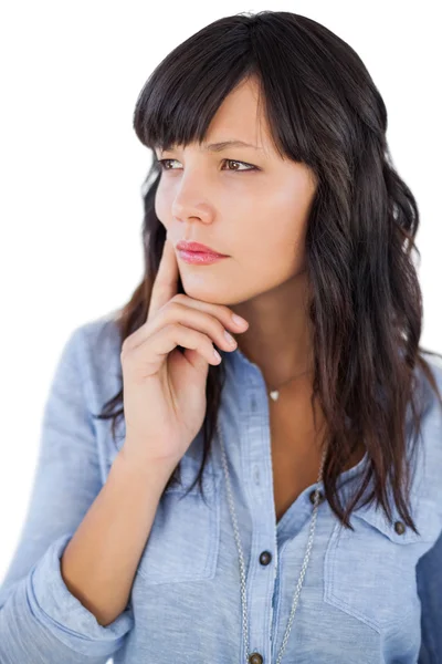 Thinking brunette with finger on her face looking away — Stock Photo, Image