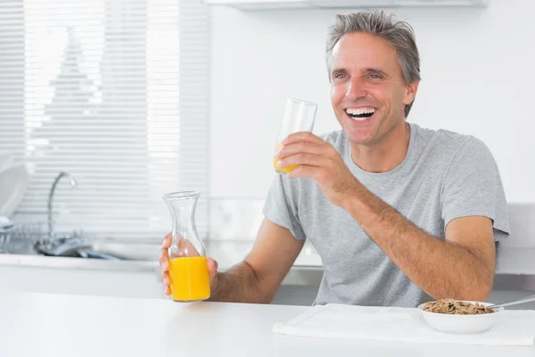 Homme heureux ayant du jus d'orange avec petit déjeuner — Photo