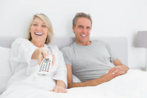 Rire couple regarder la télévision dans le lit — Photo