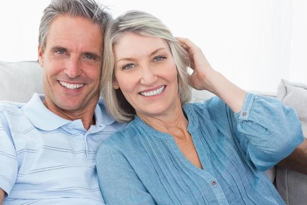 Casal sorridente em seu sofá — Fotografia de Stock