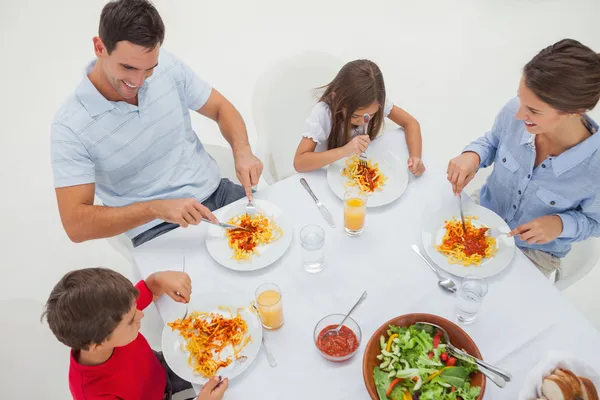 Visão geral de uma família comendo massa com molho e salada — Fotografia de Stock