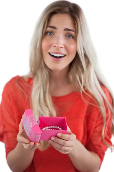 Surprised blonde woman opening gift — Stock Photo, Image