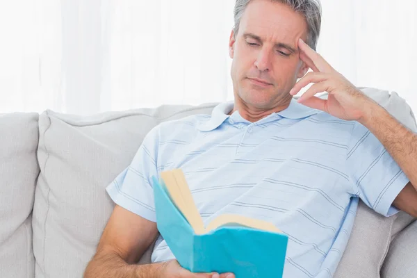 Man relaxing on his couch with a book — Stock Photo, Image