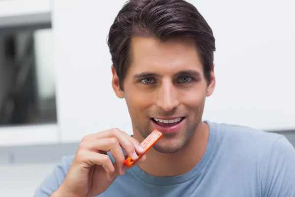 Handsome man eating a slice of bell pepper — Stock Photo, Image