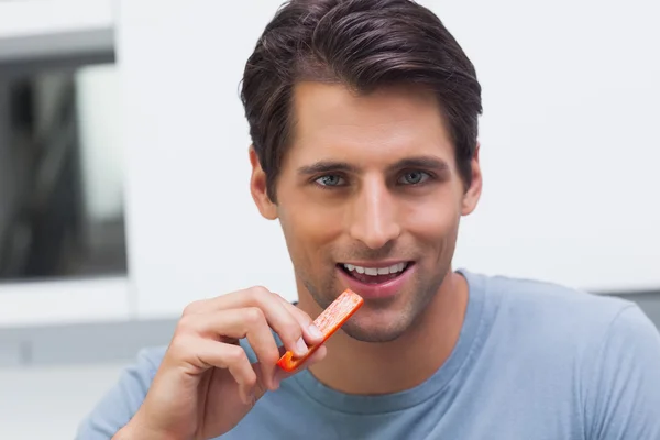 Bonito homem comendo uma fatia de pimentão — Fotografia de Stock