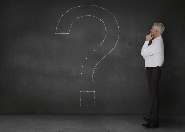 Businessman looking at a giant question mark drawn on the wall — Stock Photo, Image