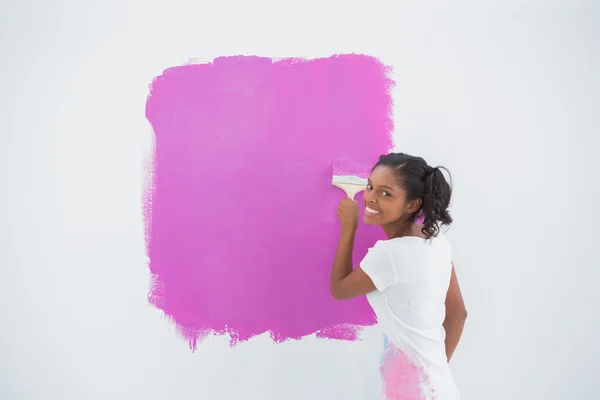 Mujer sonriente pintando su pared en rosa brillante — Foto de Stock