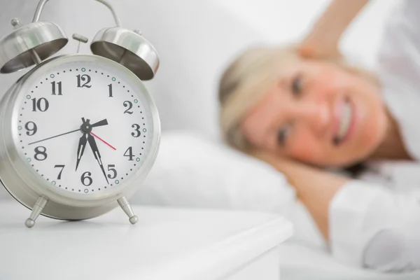 Relógio de alarme irritante mulher loira na cama — Fotografia de Stock