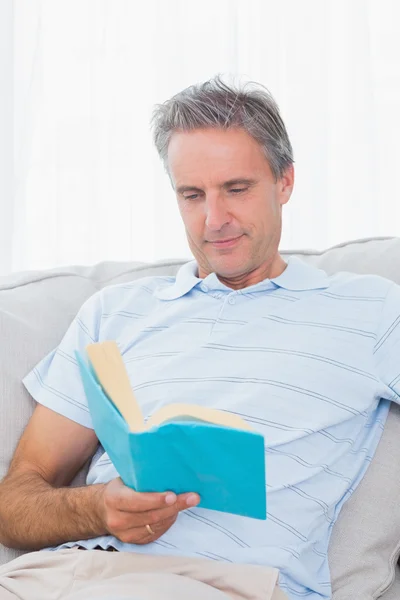 Homme relaxant sur son canapé avec un livre — Photo