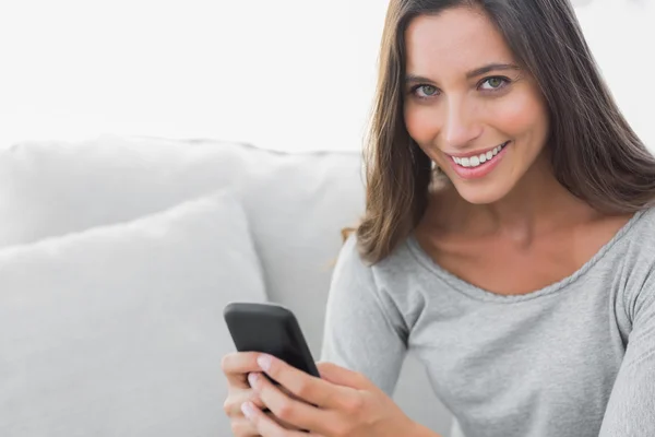 Frau schreibt SMS, während sie auf einer Couch sitzt — Stockfoto