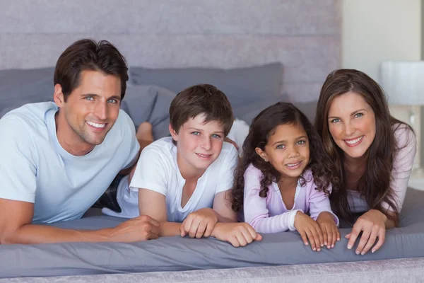 Веселая семья лежит на кровати — стоковое фото