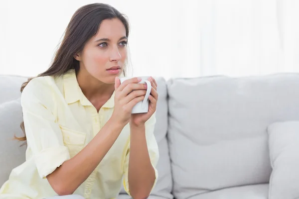 Задумчивая женщина держит чашку кофе — стоковое фото