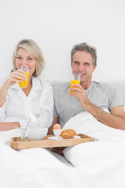 Paar frühstückt mit Orangensaft im Bett — Stockfoto