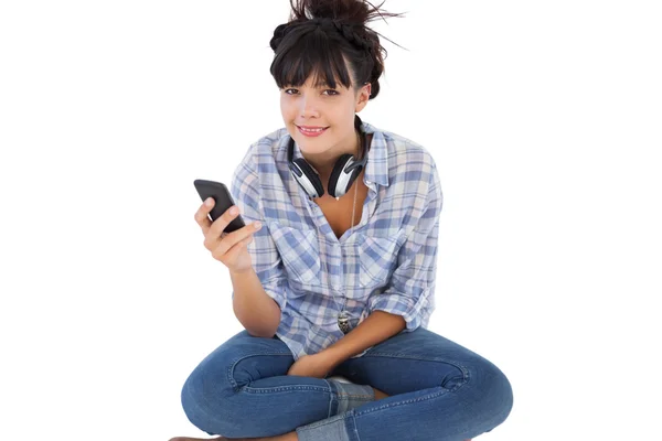 Happy young woman sitting on the floor with headphones holding h — Stock Photo, Image