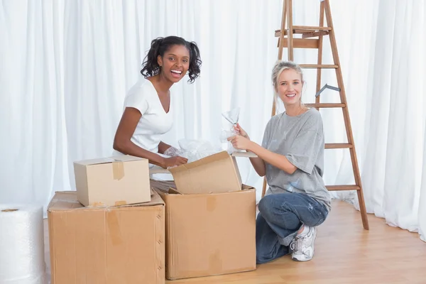 Amigos felizes desempacotando caixas em nova casa — Fotografia de Stock