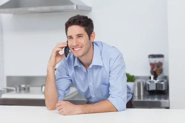 Homem tendo uma conversa telefônica na cozinha — Fotografia de Stock