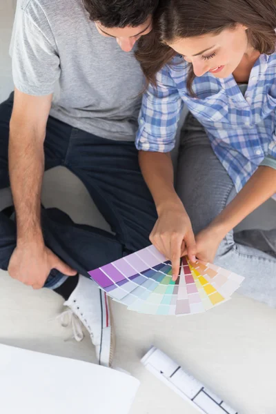 Donna che indica carte dei colori seduto nella sua nuova casa — Foto Stock