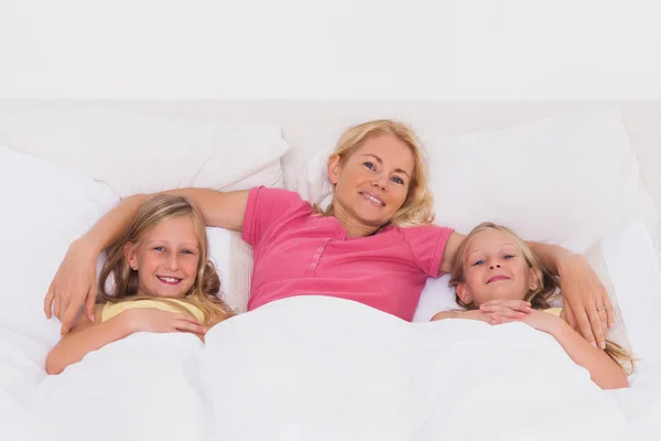Žena ležela v posteli s dětmi — Stock fotografie