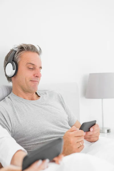 Улыбающийся человек слушает музыку на своем смартфоне — стоковое фото