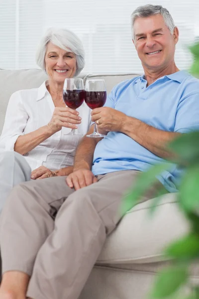 Man en vrouw rammelende hun glazen rode wijn — Stockfoto