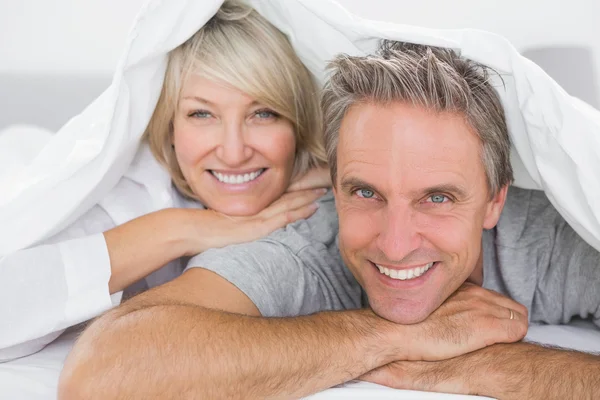 Pareja sonriendo bajo las sábanas —  Fotos de Stock