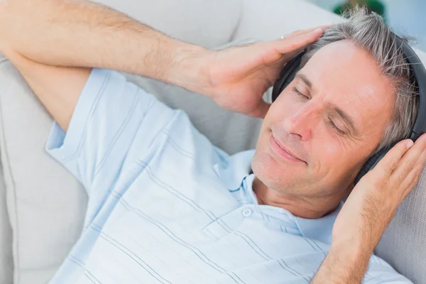 Hombre acostado en el sofá escuchando música con los ojos cerrados —  Fotos de Stock