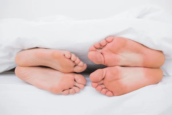 Pies de una pareja cara a cara en la cama — Foto de Stock