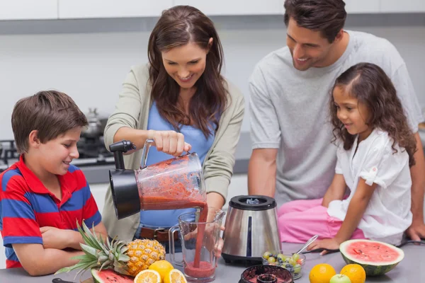 Frau mit Familie gießt Obst aus dem Mixer — Stockfoto