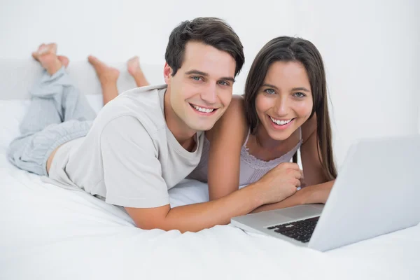 Portrait d'un couple utilisant un ordinateur portable couché au lit — Photo
