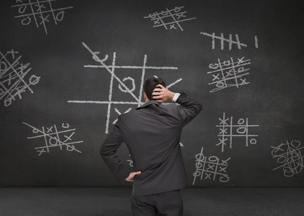 Nachdenkliche Geschäftsmann Blick auf Tic-Tac-Toe Spiel — Stockfoto