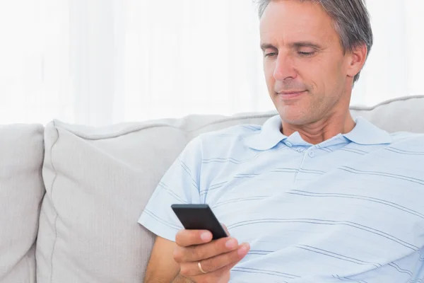 Homme relaxant sur son canapé envoyer un texte — Photo
