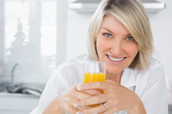 Loira feliz ter suco de laranja na cozinha — Fotografia de Stock