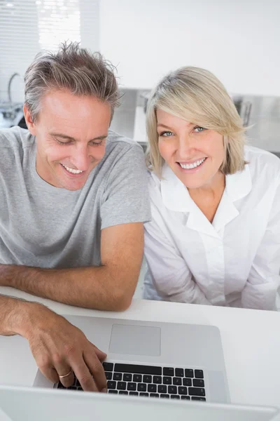 Casal sorrindo usando seu laptop pela manhã — Fotografia de Stock